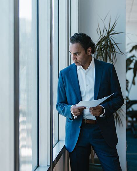 A senior executive reviewing papers by an office window